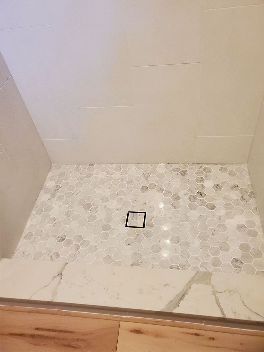 Shower with marble hexagon tile floor, white marble threshold and walls, and a center drain
