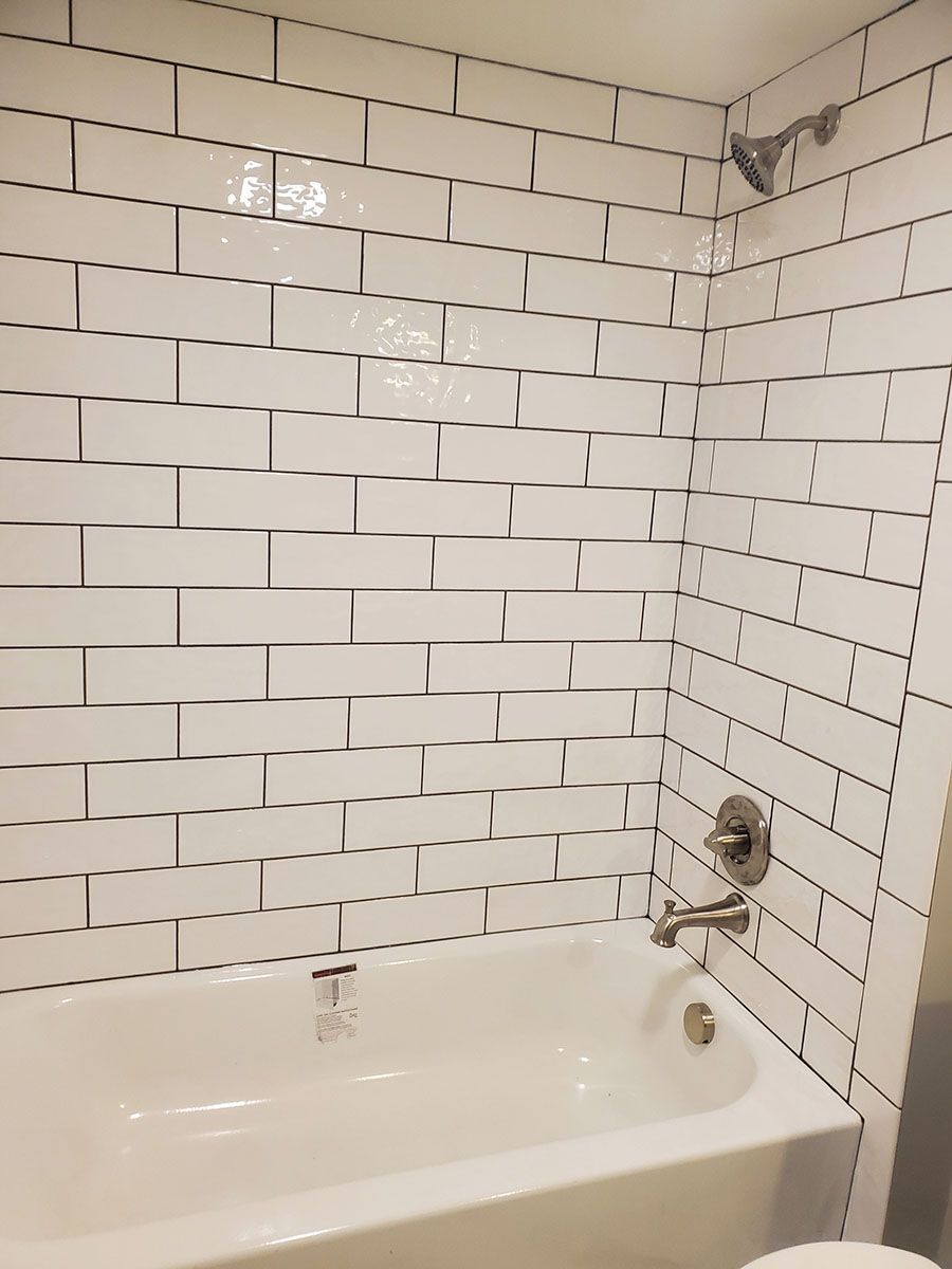 White tiled shower and tub with chrome fixtures