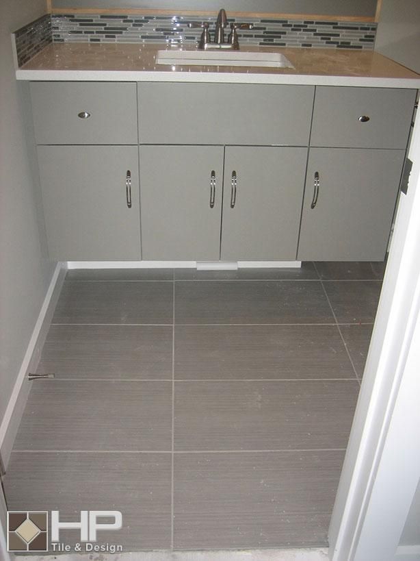 Gray bathroom with cabinets, countertop, sink, and tiled floor