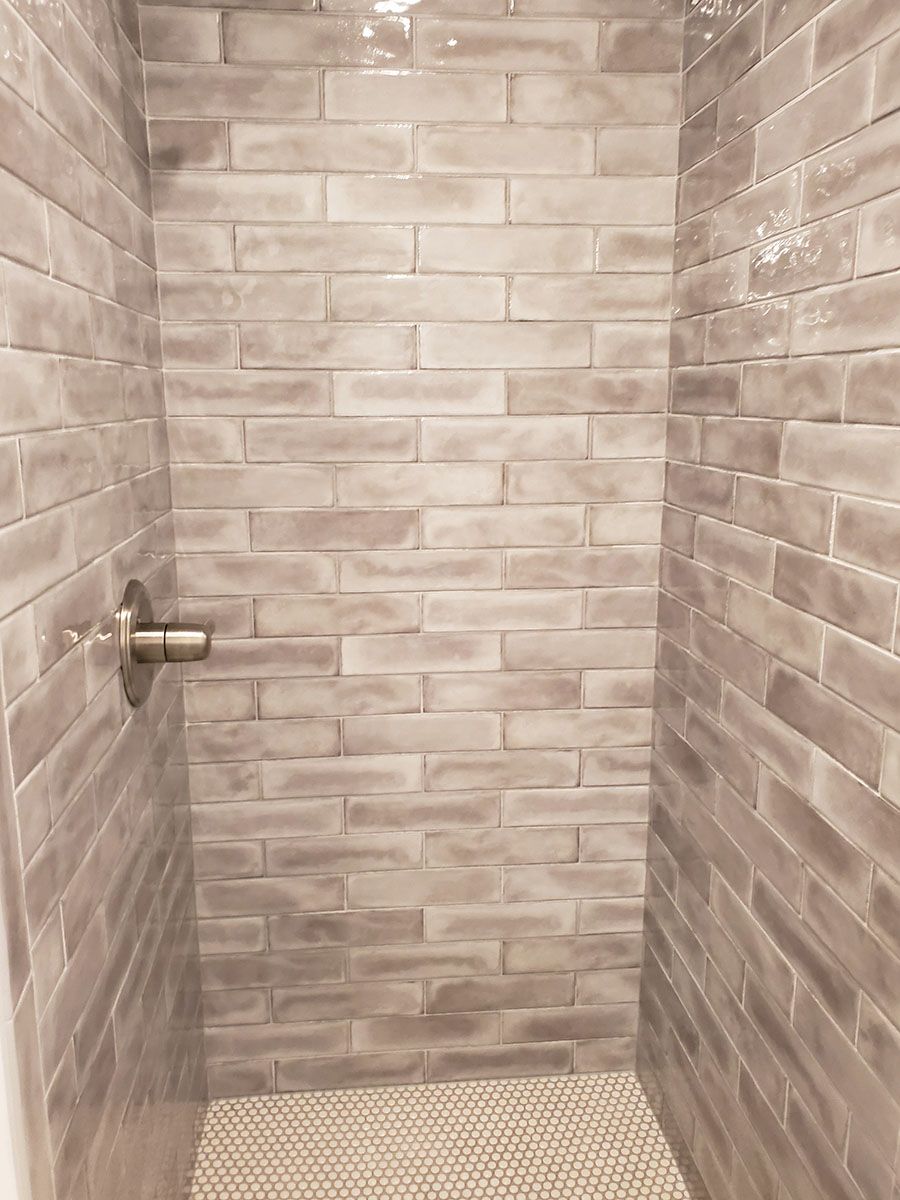 Small shower with gray brick-like tile walls and a textured floor