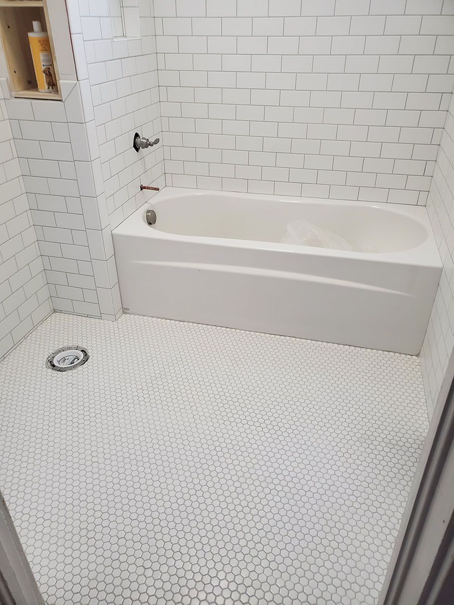 White-tiled bathroom with bathtub and shower fixtures