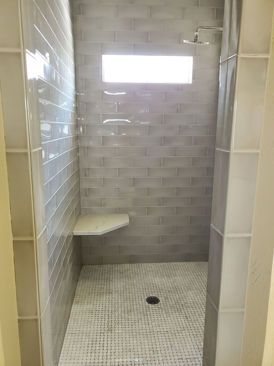 Gray-tiled shower with a built-in seat and rectangular window