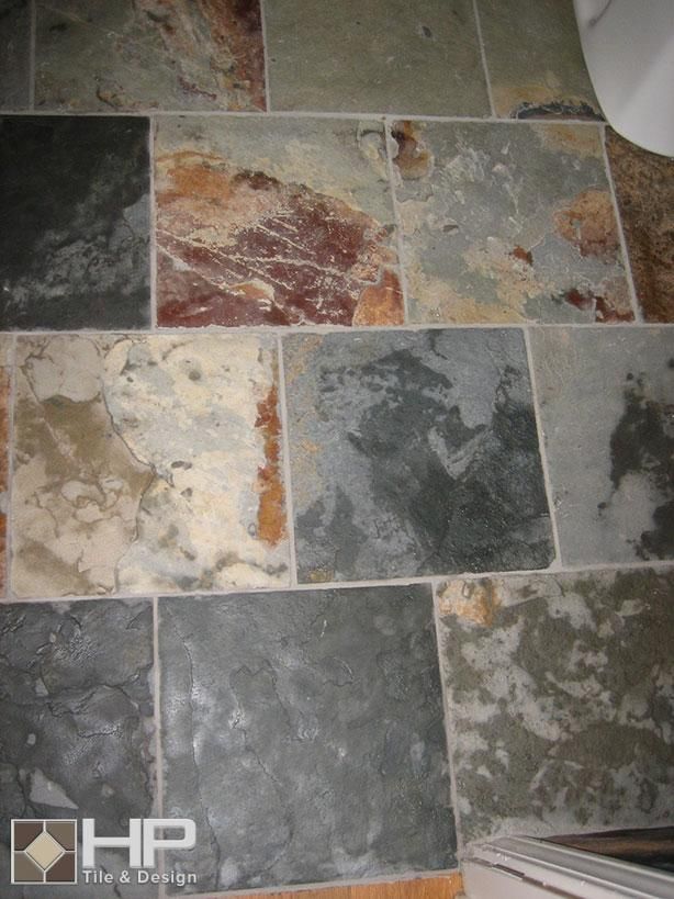 Multi-colored slate tile floor. Green, gray, brown and beige tiles with grout lines