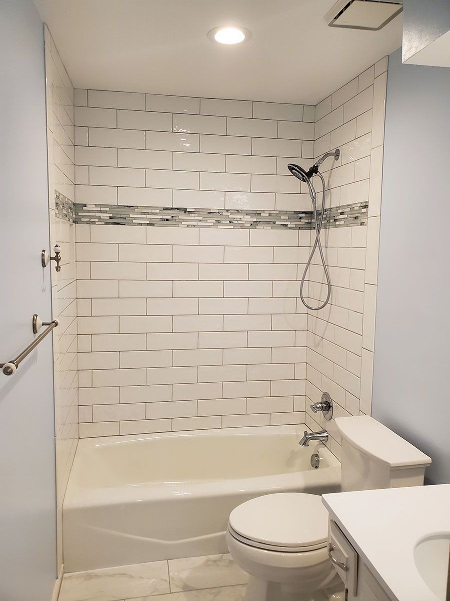 Bathroom with white tub, toilet, and tiled shower, blue walls