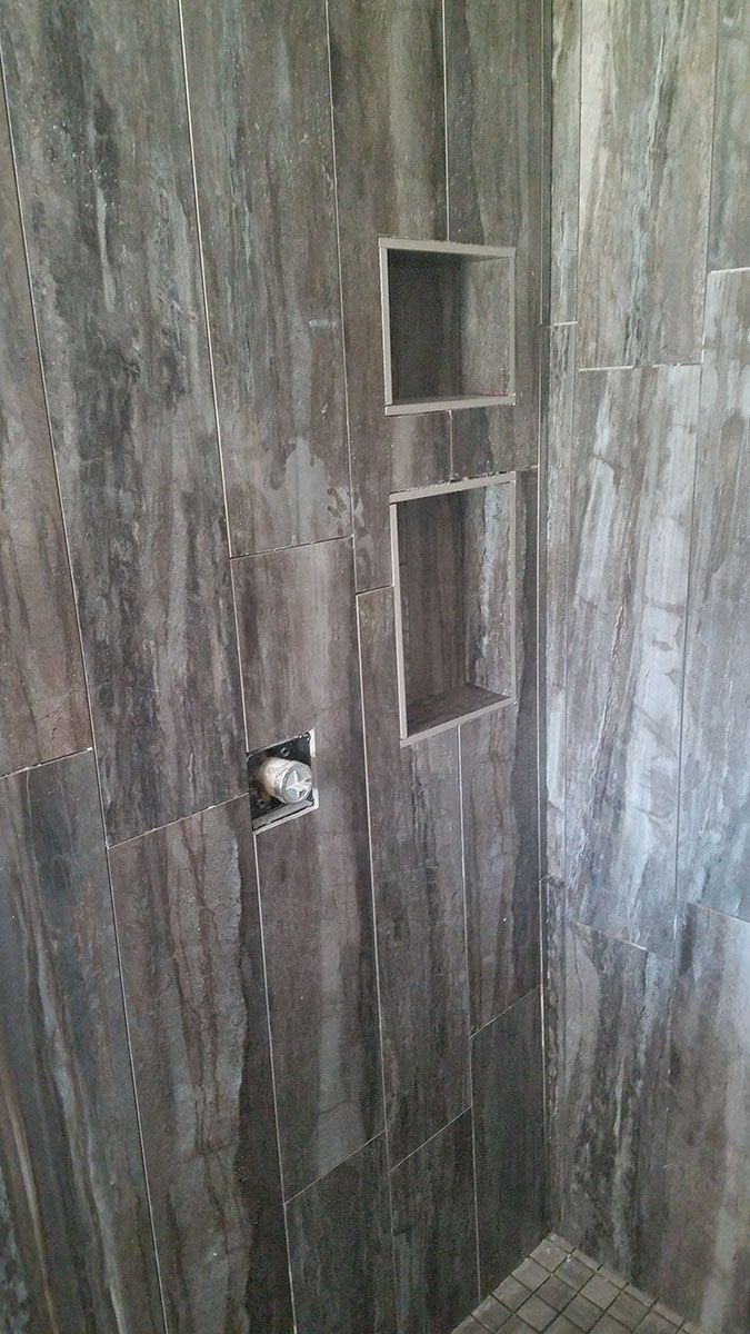 Gray tiled shower with two built-in shelves and a showerhead
