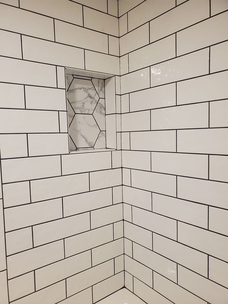 White tiled shower interior with a built-in hexagonal niche