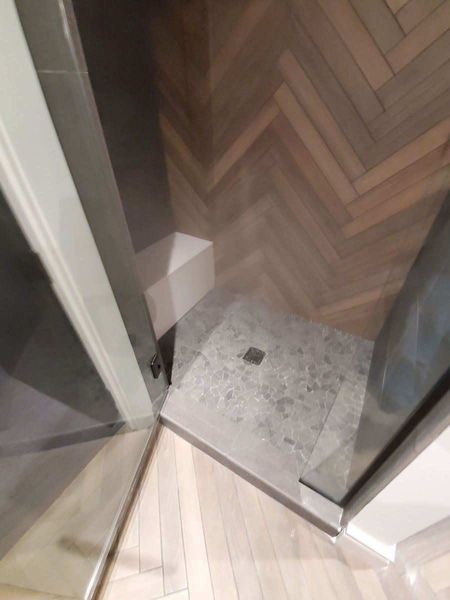 Shower stall with gray tile base, wooden herringbone floor