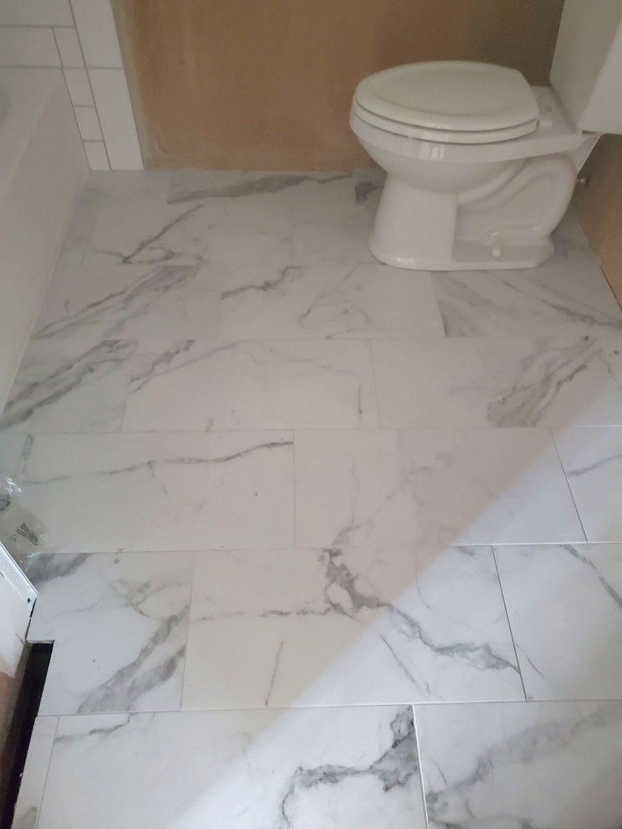 White marble-patterned tile bathroom floor with a white toilet