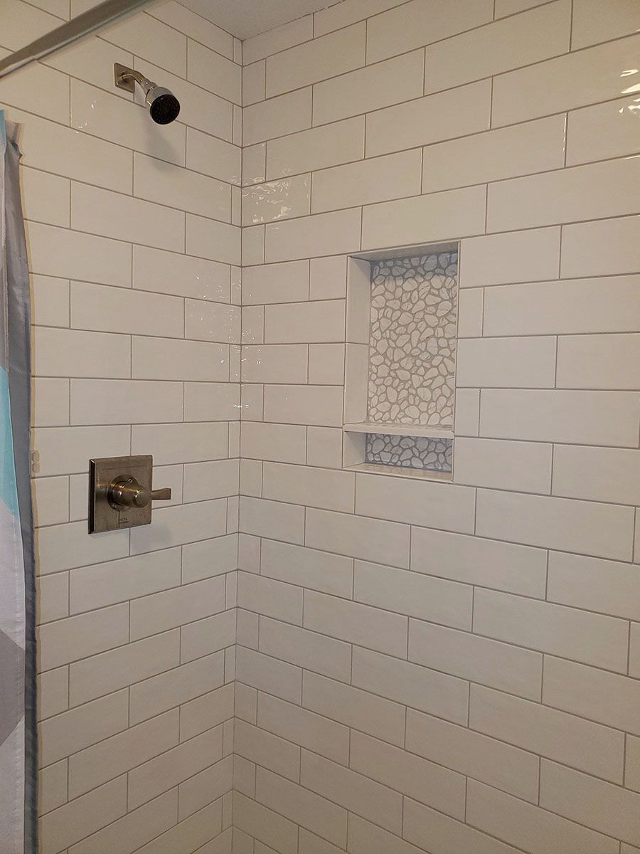 White tiled shower with a niche and shower fixtures
