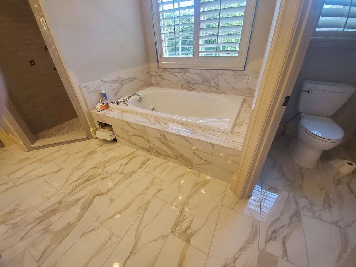 Bathroom with marble tile, a bathtub, a shower, and a toilet