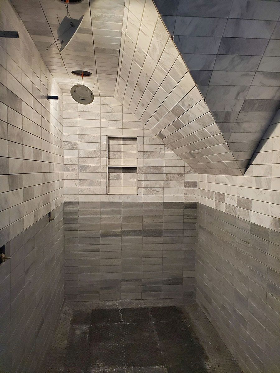 Empty shower stall with gray tiled walls and ceiling