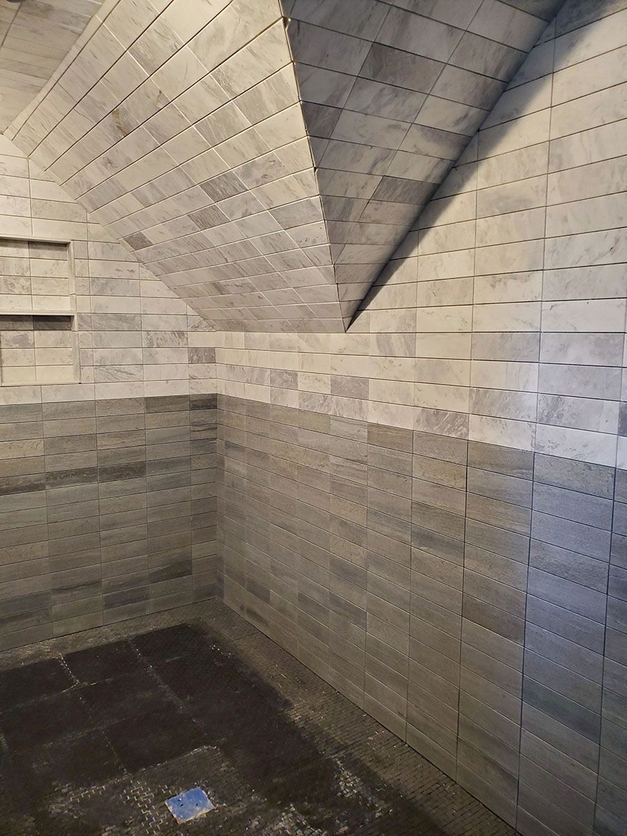 Gray tiled shower with vaulted ceiling and built-in shelf