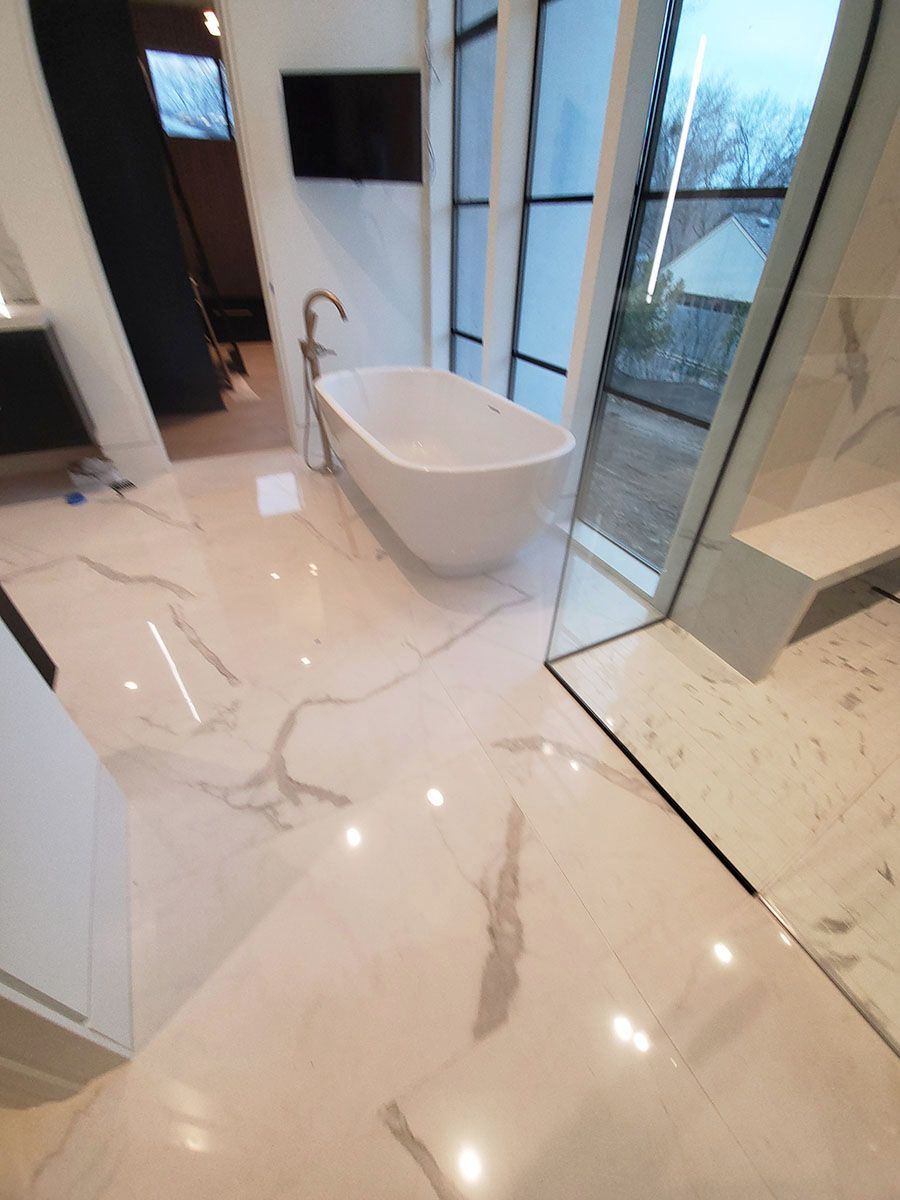 Bathroom with marble floor, white tub, modern fixtures, and large window