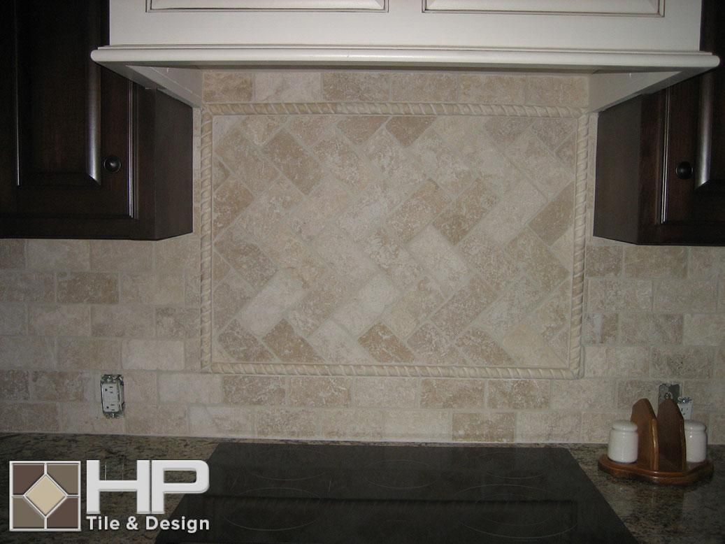 Kitchen backsplash with beige and brown tiles beneath cabinets and stove.