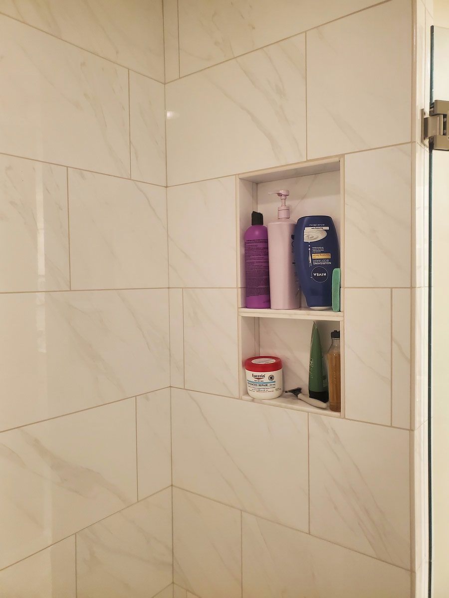 Tiled shower interior with a built-in shelf holding toiletries