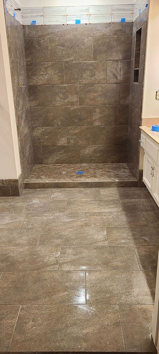 A newly tiled shower stall with matching floor tiles, in a bathroom setting