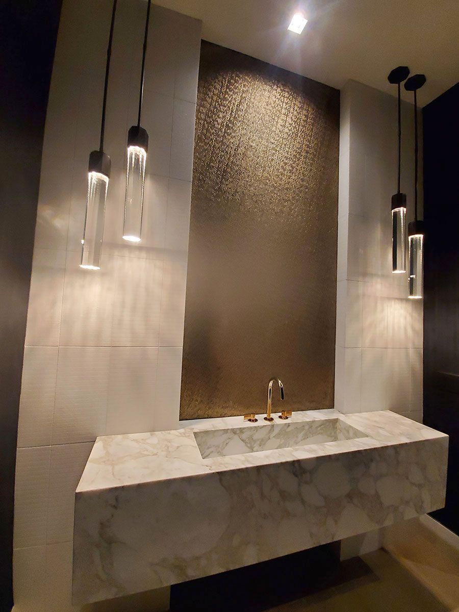 Modern bathroom with floating marble vanity, gold fixtures, and pendant lights