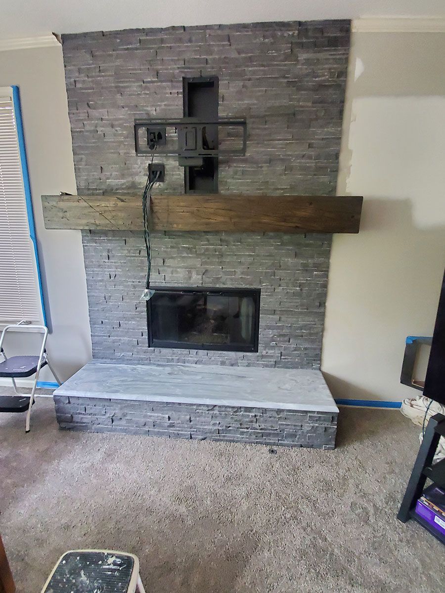 Stone fireplace with a wooden beam mantel and a mounted TV bracket