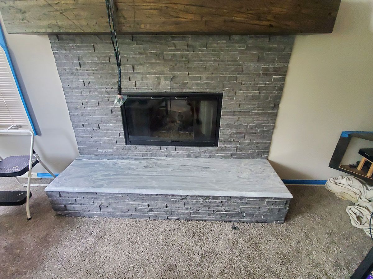 Fireplace with gray stone facing and wooden mantle