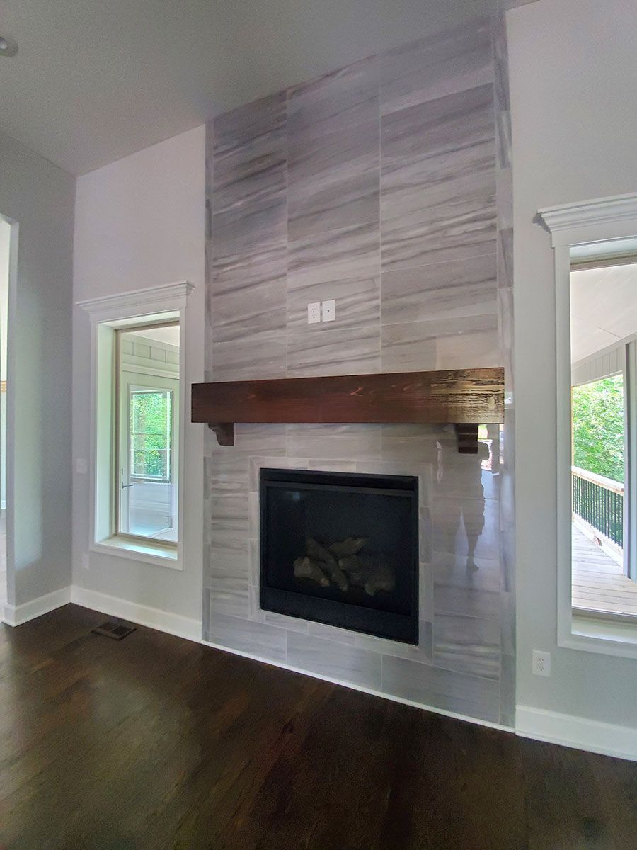 Fireplace with gray tiled surround, wooden mantle, and dark wood floors