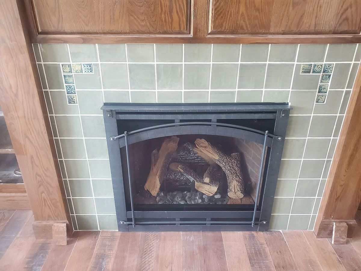 Fireplace with sage green tiled surround and wooden mantel