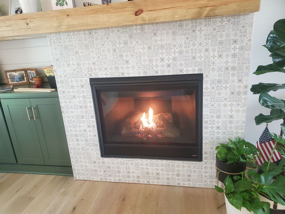 Fireplace with lit fire, tiled surround, and wooden mantel