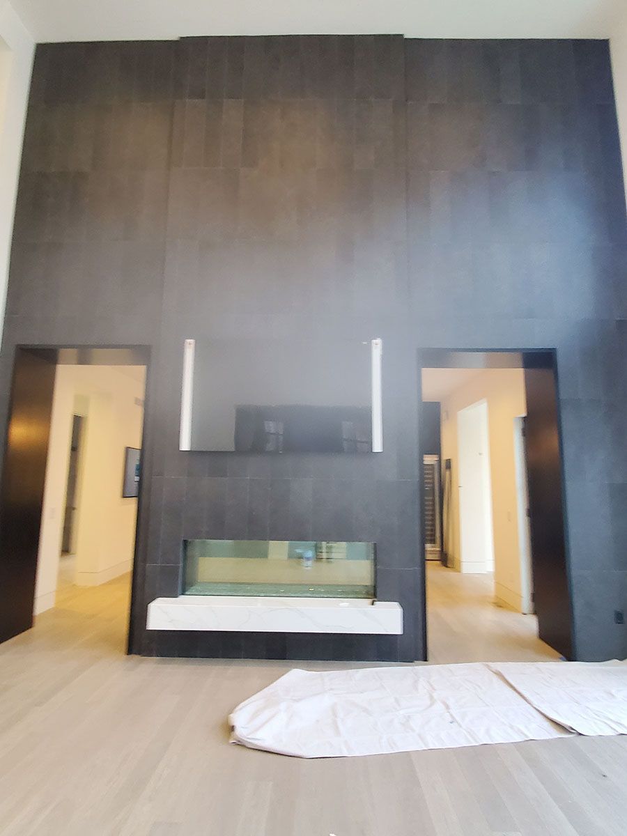 Modern fireplace with dark tile wall, TV, and openings to rooms on either side