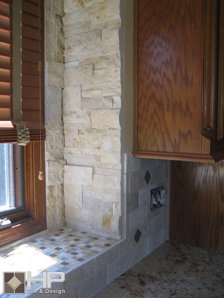 Kitchen corner with stone wall, window, and wooden cabinetry.