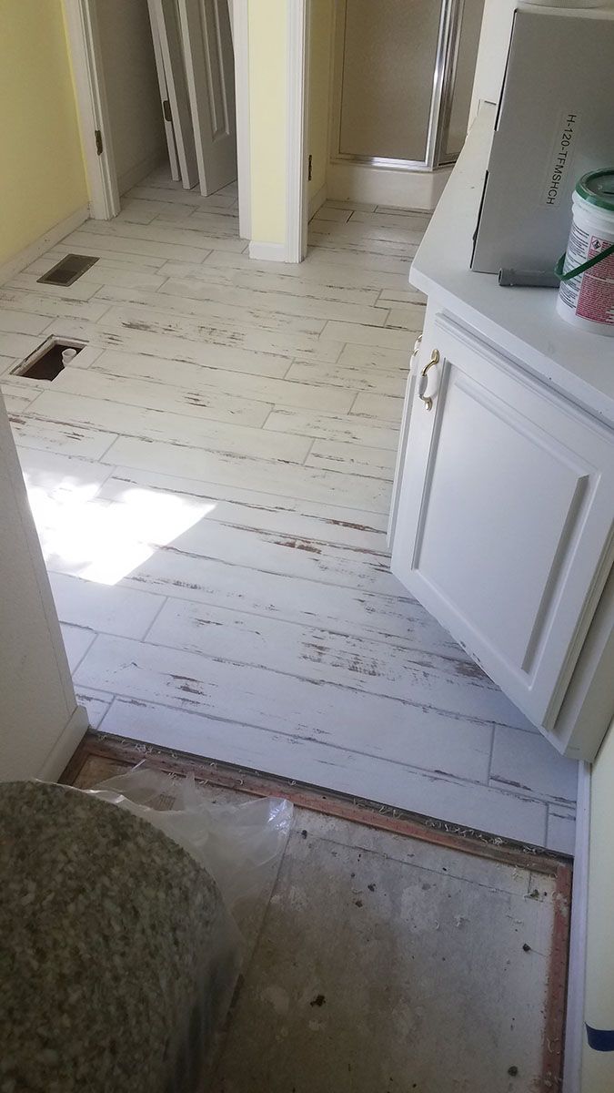 White painted wood floor in disrepair with cabinet and open space, interior view