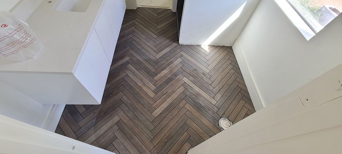 Herringbone wood floor in a hallway with white walls and a cabinet