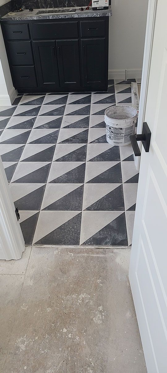Bathroom with black and white triangle tile flooring and a black vanity