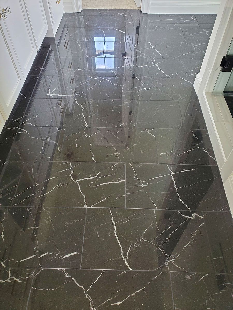 Black marble tiled hallway with white veining, reflecting light