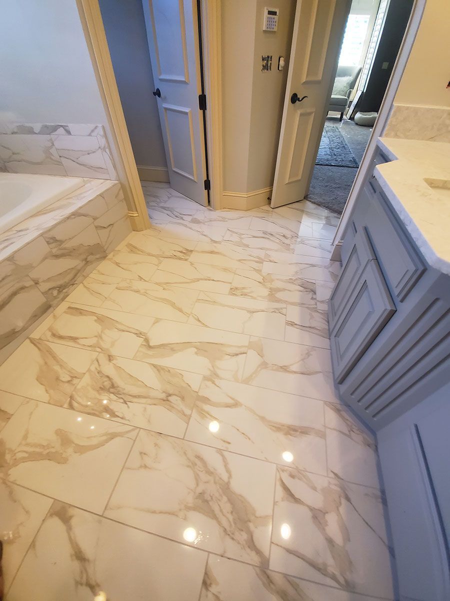 Bathroom with marble-patterned tile floor, light blue vanity, and doorway