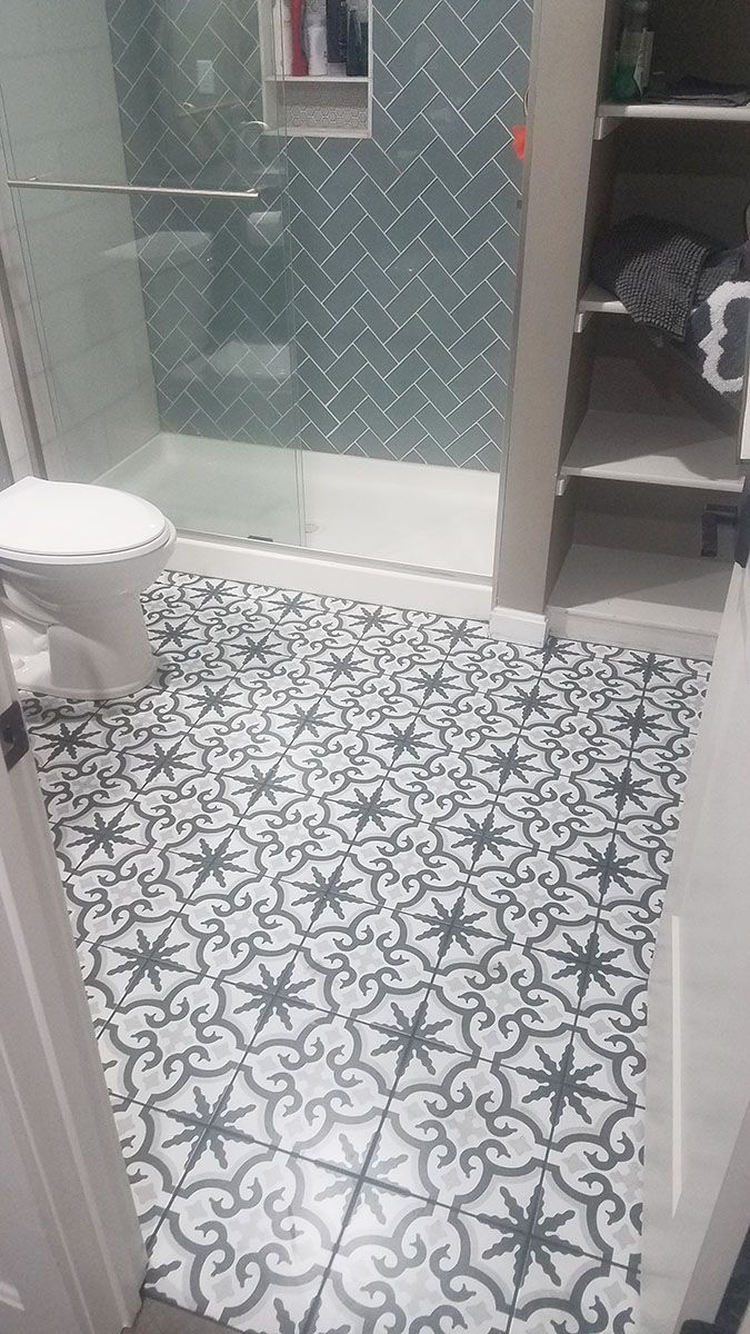 Bathroom with patterned floor tiles, glass shower, and white toilet