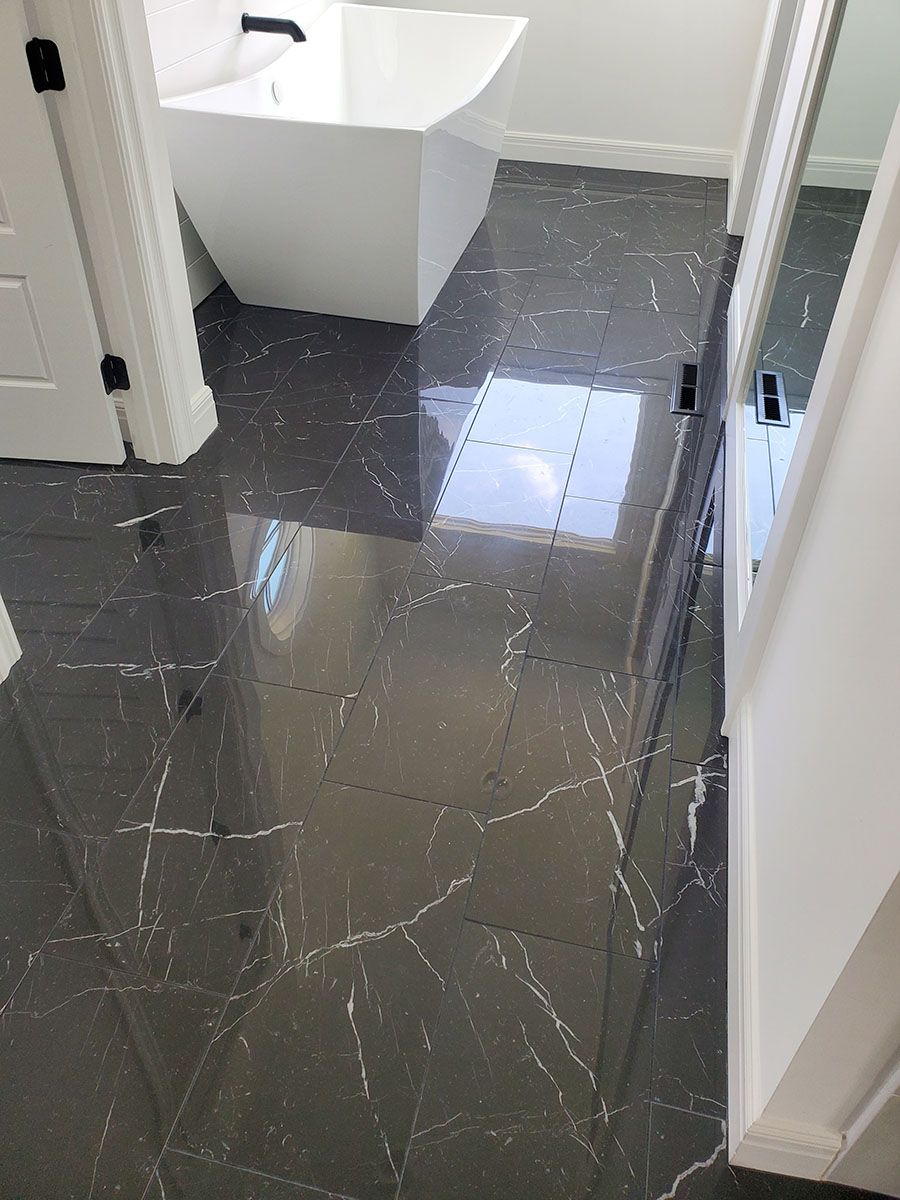 Bathroom with dark gray, marble-look tiled floor, a white angular sink, and white trim