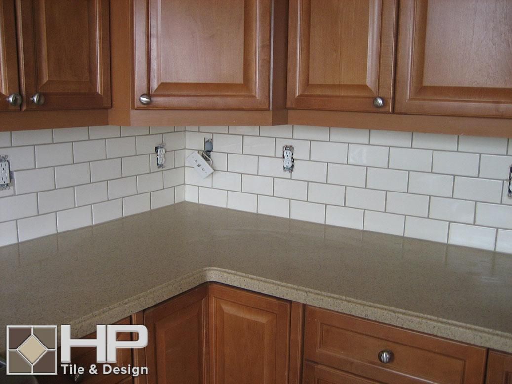 Kitchen with brown cabinets, beige countertop, and white subway tile backsplash.