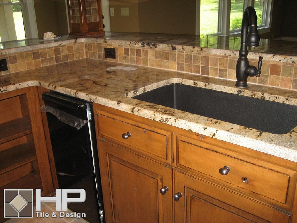 Kitchen with granite countertops, wooden cabinets, black sink, and tile backsplash.