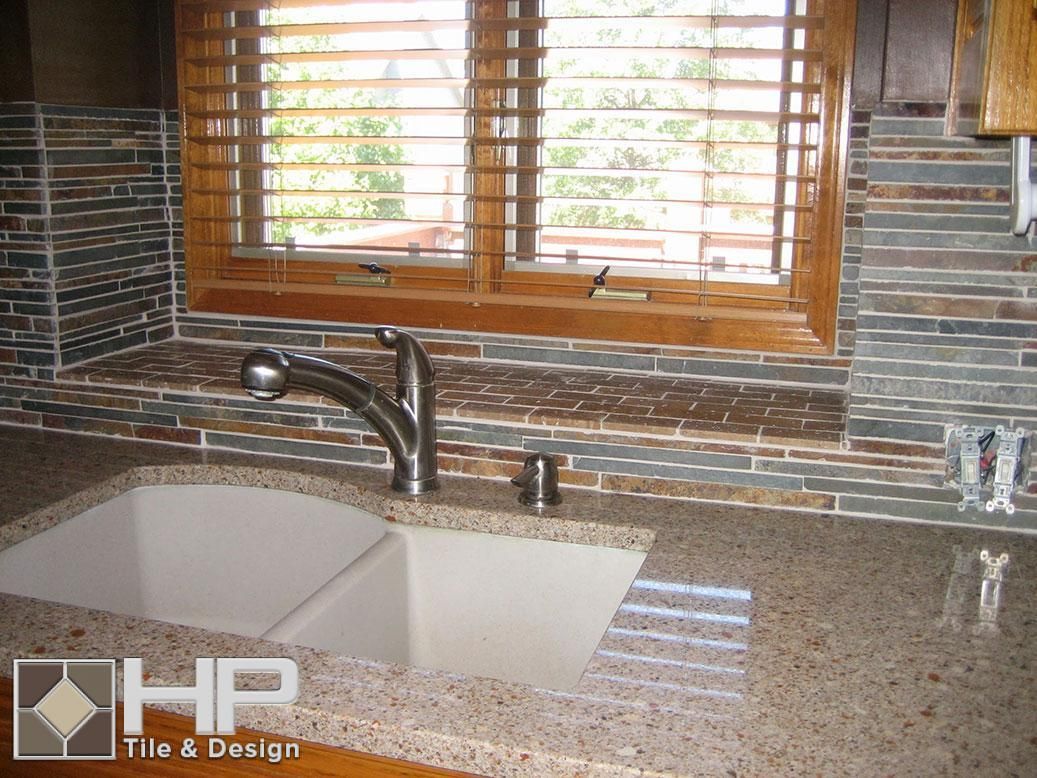 Kitchen with stone backsplash, sink, faucet, window with blinds, and speckled countertop.