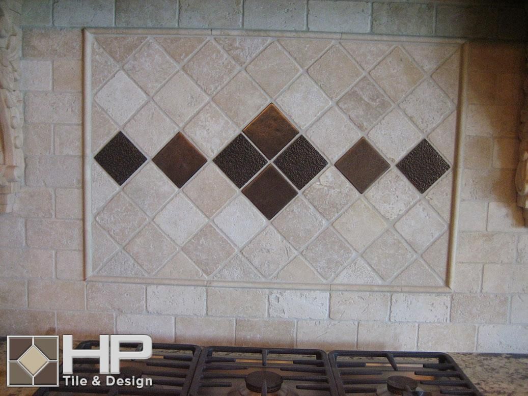 Kitchen backsplash with diamond pattern of beige and brown tiles. A stove is in the foreground.