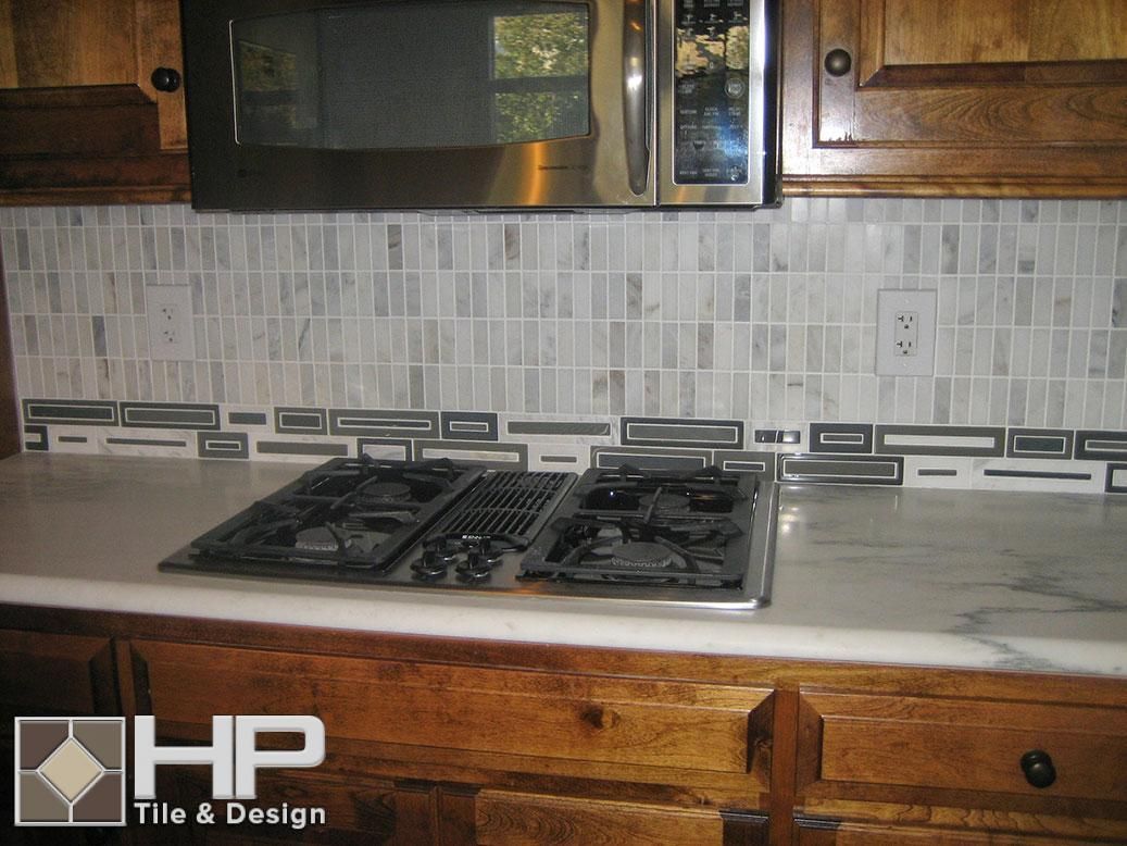 Kitchen with a stainless steel microwave, gas stovetop, and a mosaic tile backsplash.