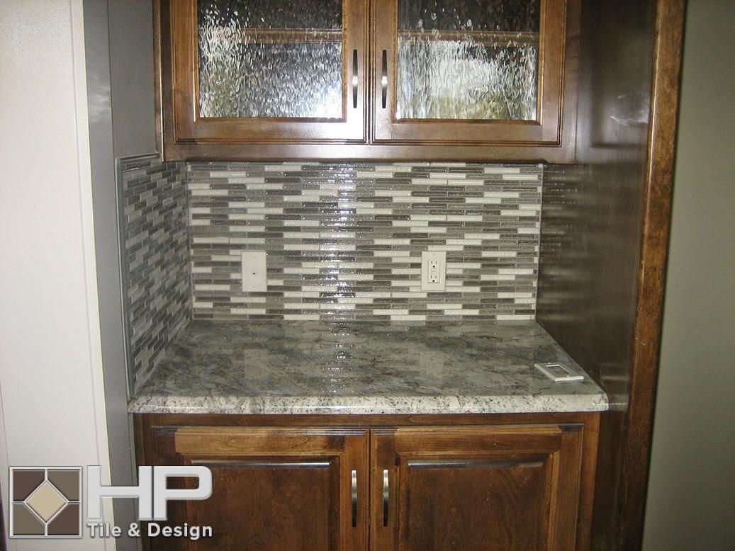 Kitchen with dark wood cabinets, patterned backsplash, and granite countertop.