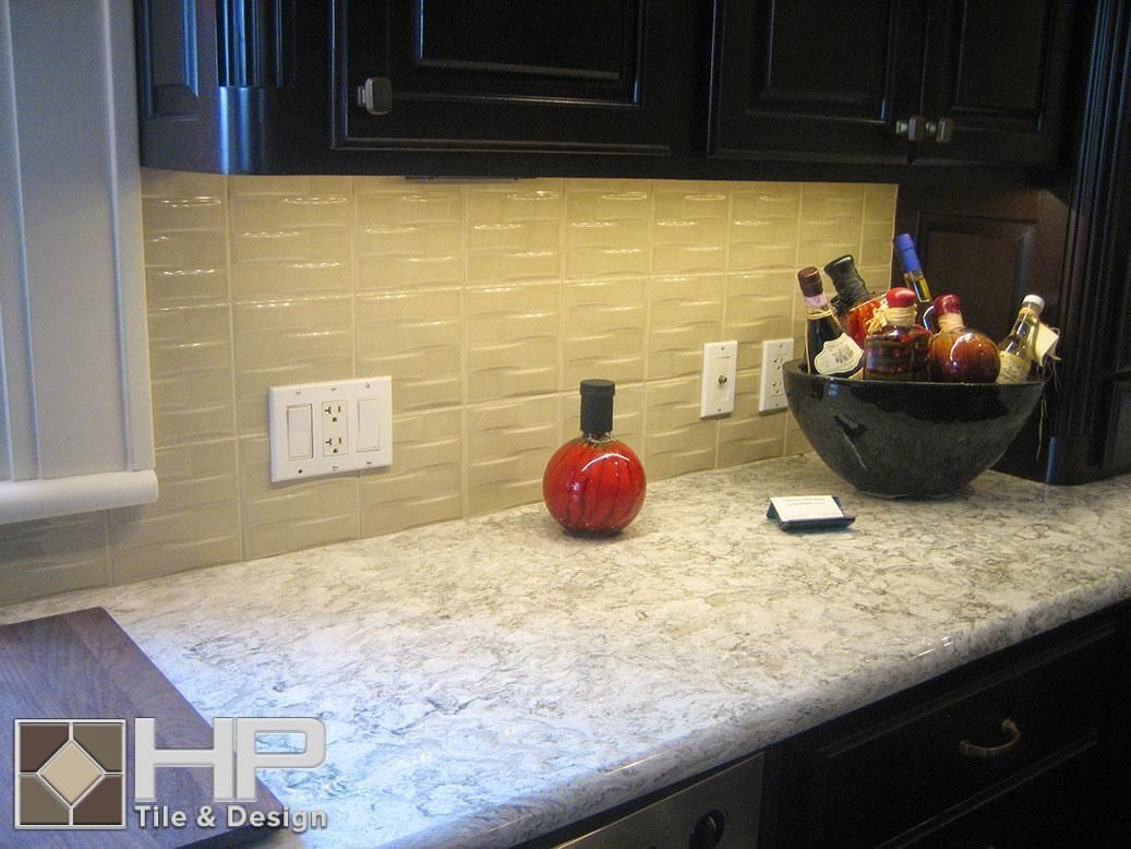 Kitchen with beige backsplash, speckled countertops, and black cabinets.