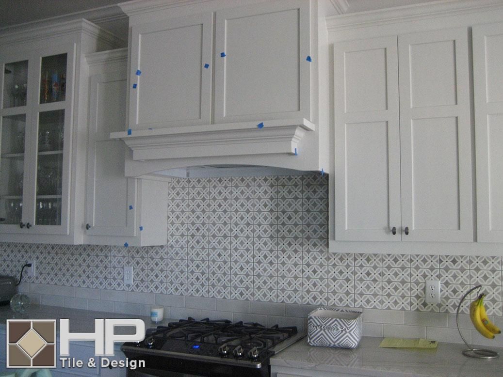 White kitchen cabinets with a patterned backsplash over a gas stove.