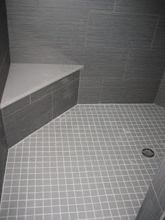 Gray tiled shower with a corner bench.