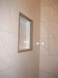 Shower wall with recessed shelf, tiled with marble-like white tiles
