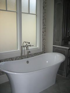 White freestanding bathtub by frosted bathroom window
