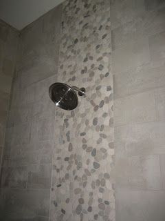Shower with gray tile, a vertical stripe of pebble tile, and a silver showerhead