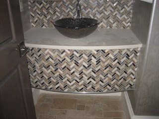 Bathroom vanity with chevron mosaic tile, glass bowl sink, and stone countertop