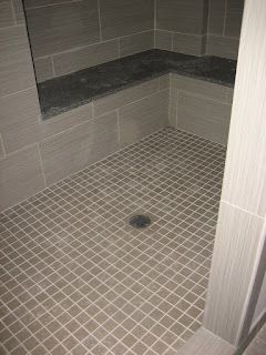 Gray tiled shower with corner bench seat and floor drain