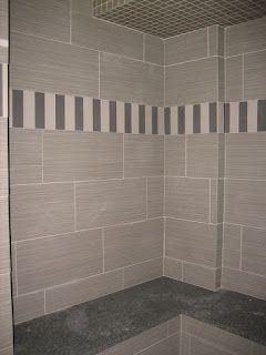 Gray tiled shower with a decorative stripe and a dark stone bench